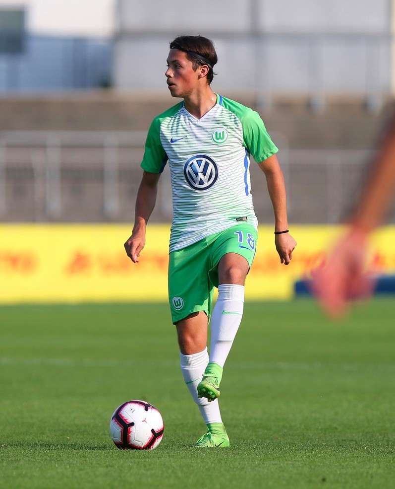 Adrian Goransch, number 18, on the ball in VfL Wolfsburg's green and white youth kit